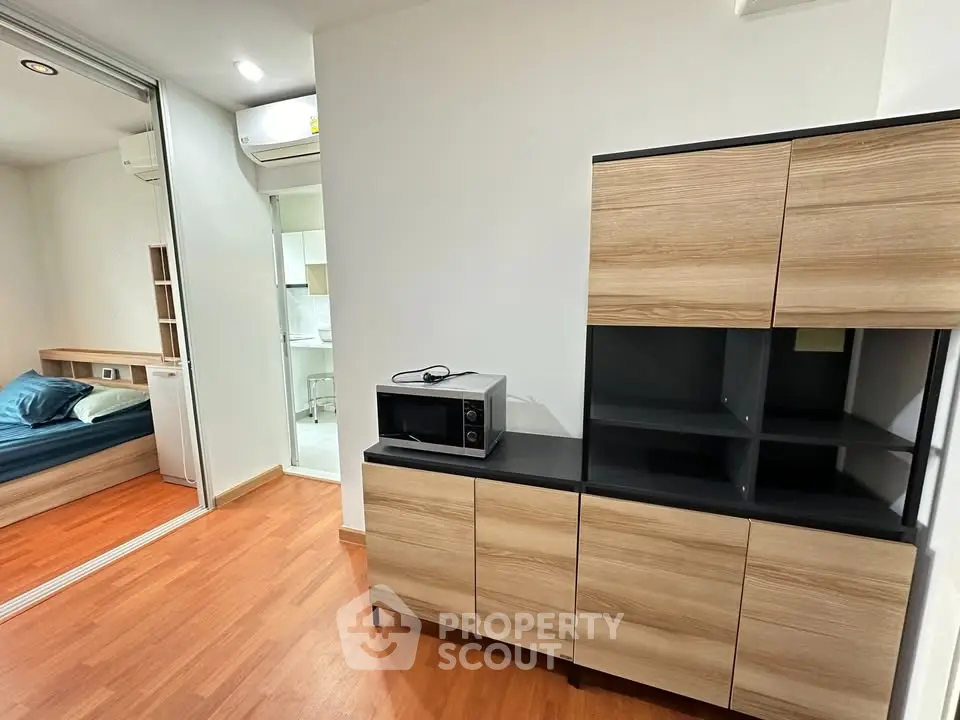Modern apartment interior with wooden flooring and sleek storage cabinets, featuring a cozy bedroom view.