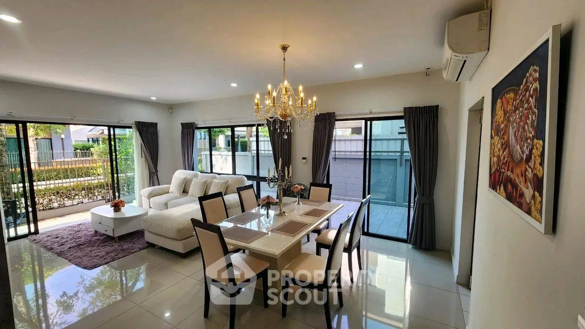 Spacious living and dining area with elegant chandelier and garden view