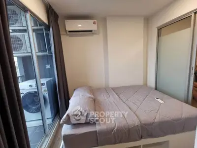 Cozy bedroom with modern air conditioning and adjacent laundry area featuring a washing machine.