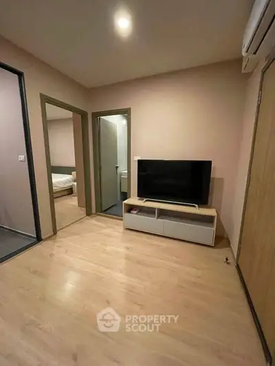 Modern living room with sleek TV setup and wooden flooring in cozy apartment.