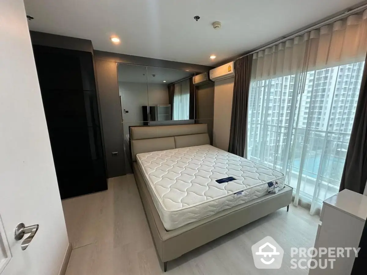 Modern bedroom with large windows and city view, featuring a comfortable bed and sleek design.