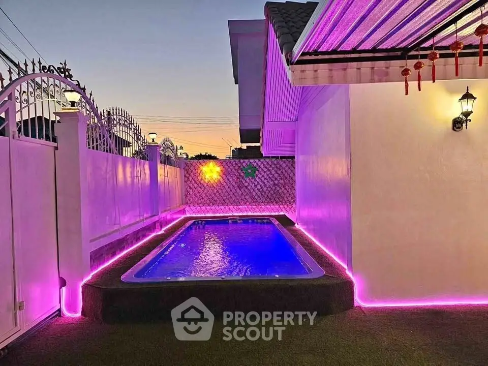 Charming backyard pool with vibrant LED lighting and elegant fencing at sunset.