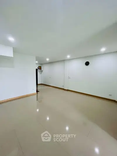 Spacious empty room with glossy tiled flooring and recessed lighting, ideal for customization.