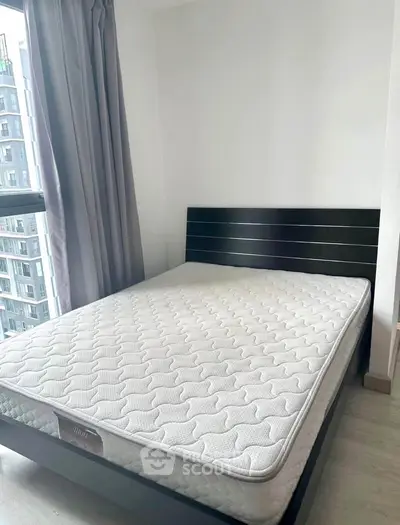 Modern bedroom with large window and city view, featuring a sleek black bed frame and comfortable mattress.