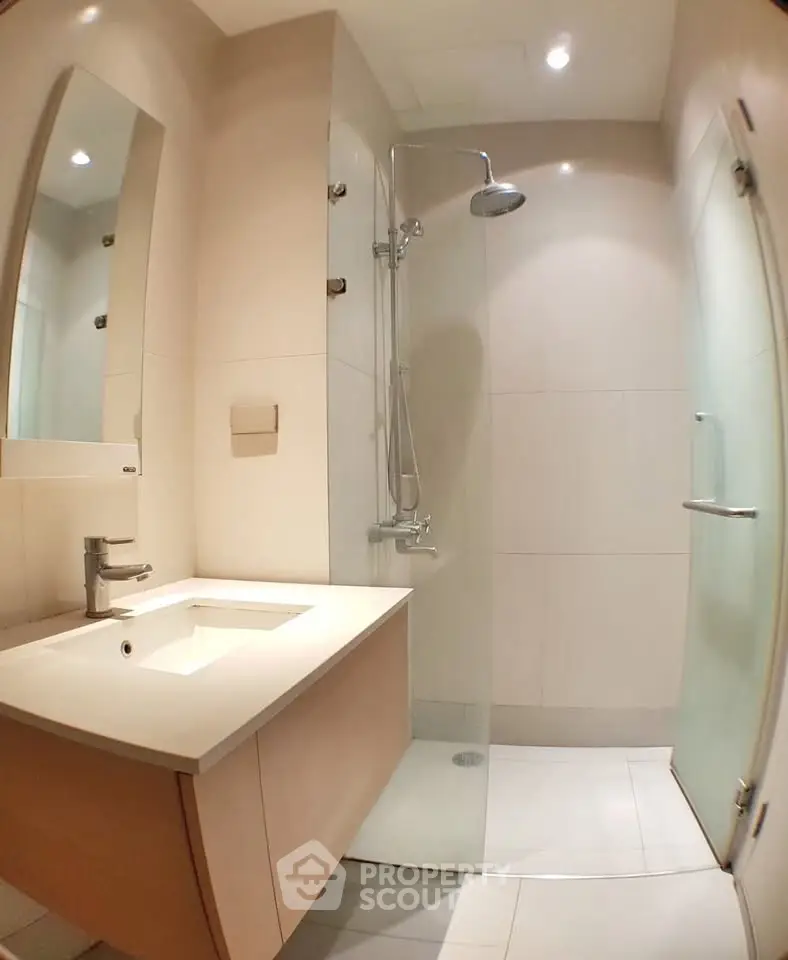 Modern bathroom with sleek shower and elegant vanity in contemporary apartment.