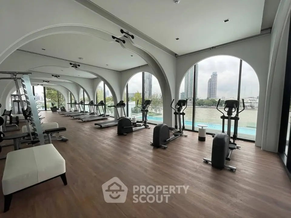 Luxurious gym with stunning river view and modern equipment in high-end residential building.
