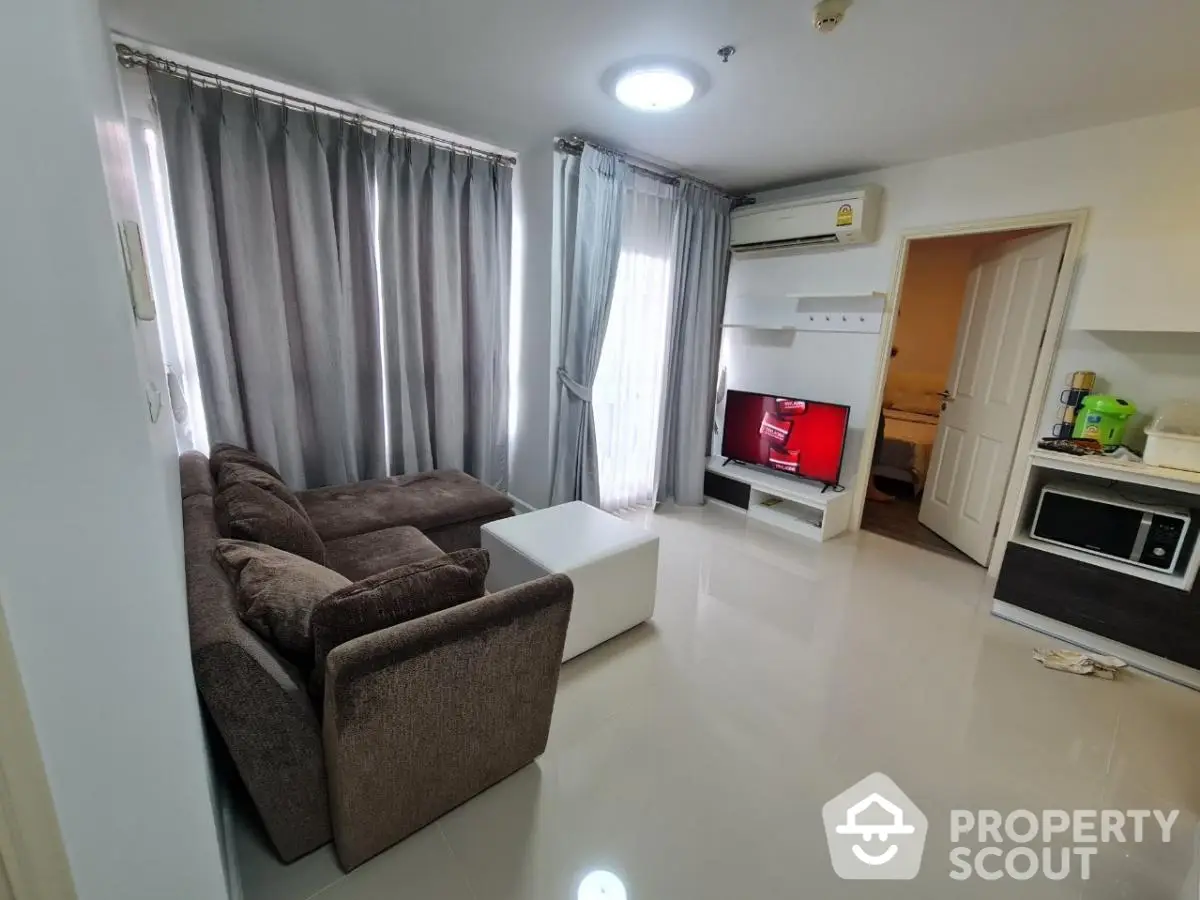 Modern living room with cozy brown sofa, sleek TV setup, and natural light from large windows.