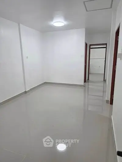 Spacious empty room with glossy tiled flooring and white walls, ideal for customization.