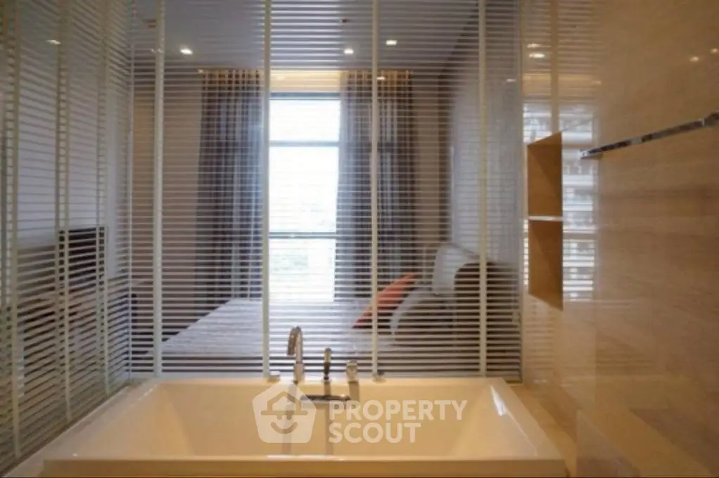 Luxurious bathroom with modern bathtub and bedroom view through glass partition.