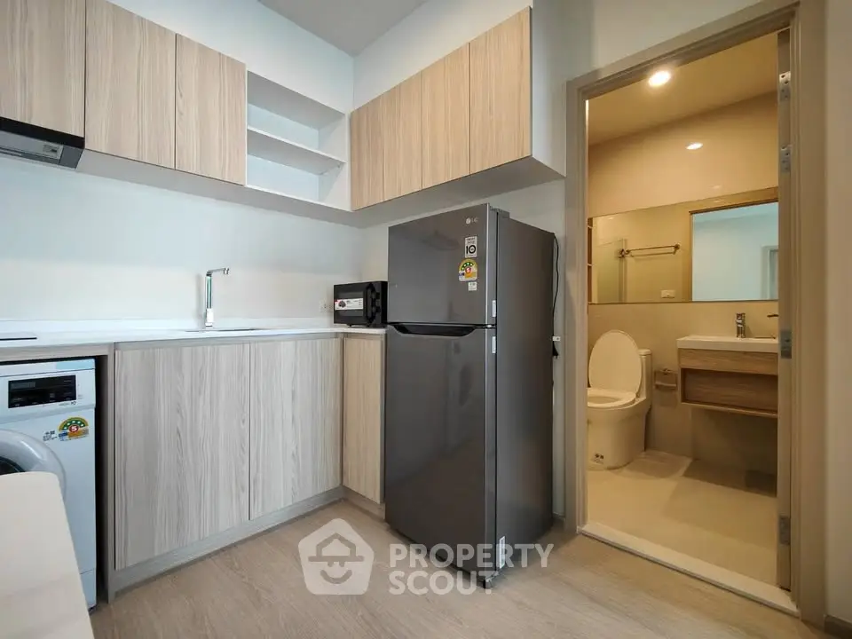 Modern kitchen with sleek cabinetry and integrated appliances next to a compact bathroom.