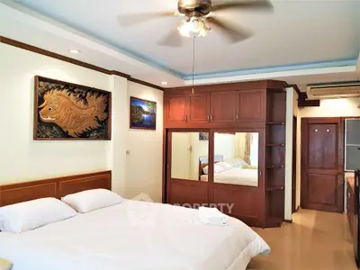 Spacious bedroom with elegant wooden furniture and ceiling fan in modern apartment.