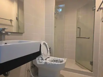 Modern bathroom with sleek fixtures and glass shower enclosure in a contemporary apartment.