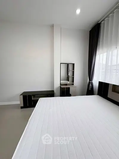 Modern minimalist bedroom with sleek furniture and large window for natural light.