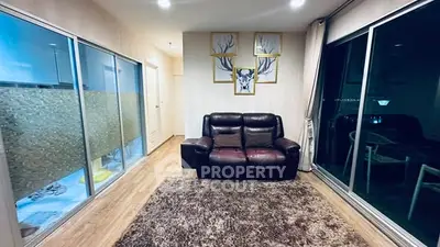 Modern living room with leather sofa, large windows, and stylish decor in a cozy apartment.