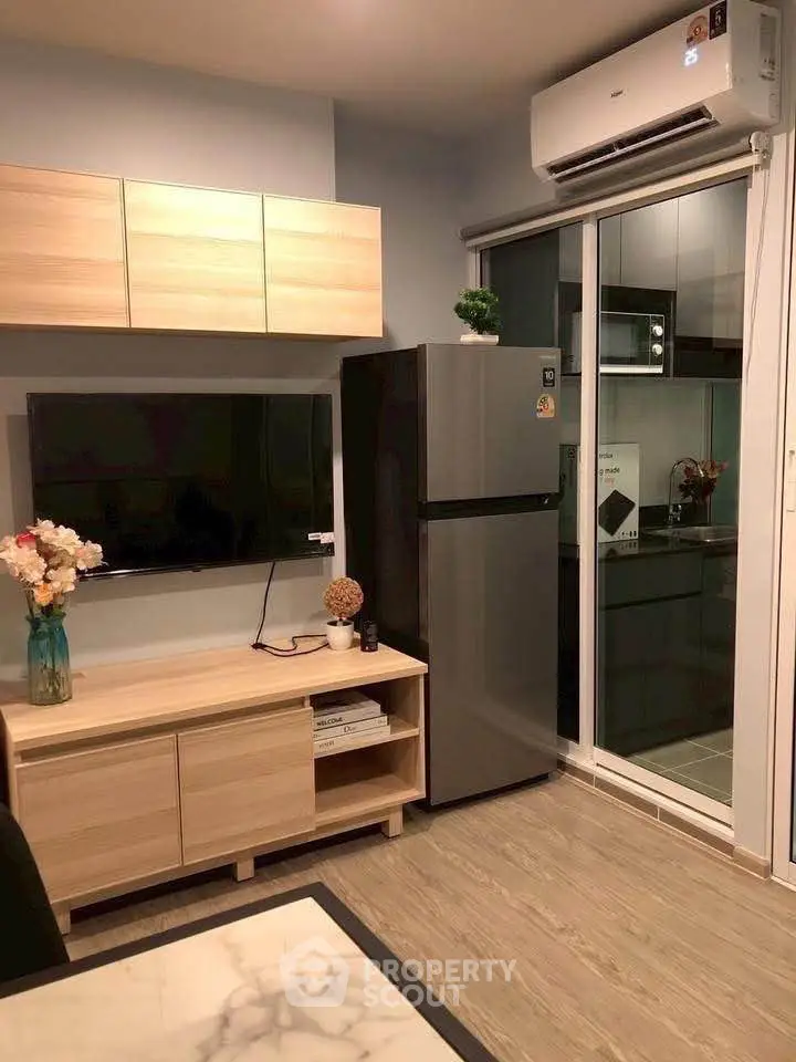 Modern living room with sleek kitchen, featuring stylish cabinetry and stainless steel appliances.