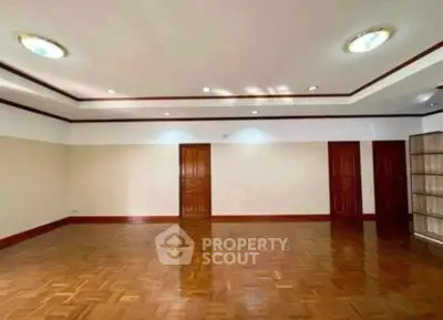 Spacious empty room with polished wooden floors and elegant ceiling lights.