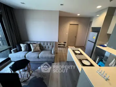 Modern living room with sleek kitchen and stylish decor in open layout apartment.