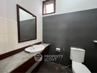 Modern bathroom with sleek design and large mirror, featuring a stylish sink and toilet.