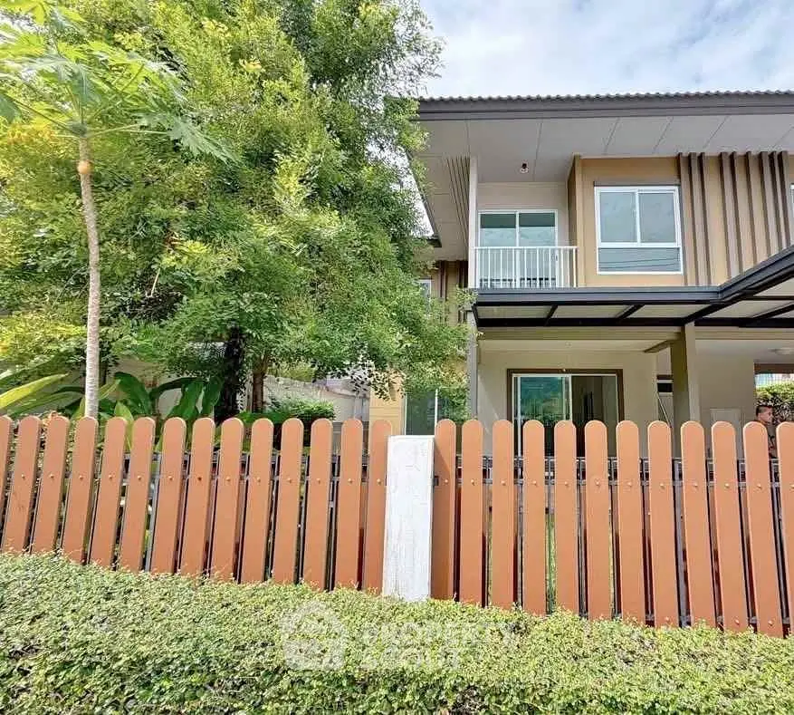 Charming two-story house with lush garden and wooden fence