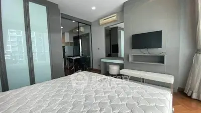 Modern bedroom with sleek design, featuring a wall-mounted TV and large windows for natural light.