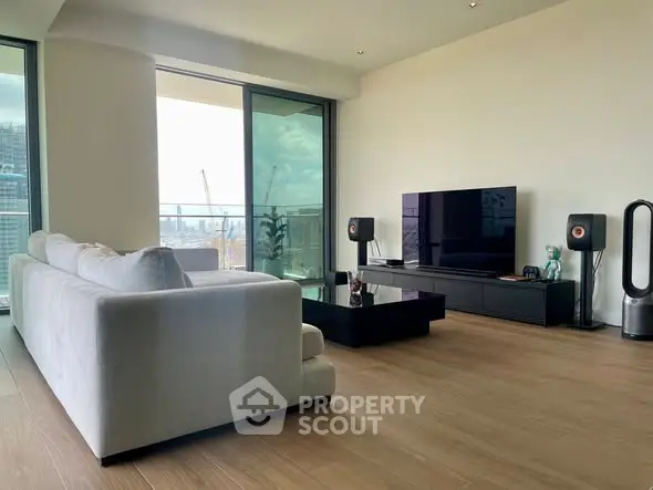 Modern living room with sleek furniture and large balcony offering city views.