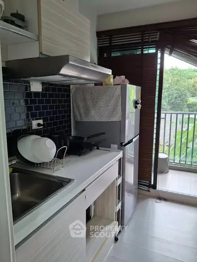 Modern kitchen with sleek design and balcony view, featuring stainless steel appliances and ample natural light.