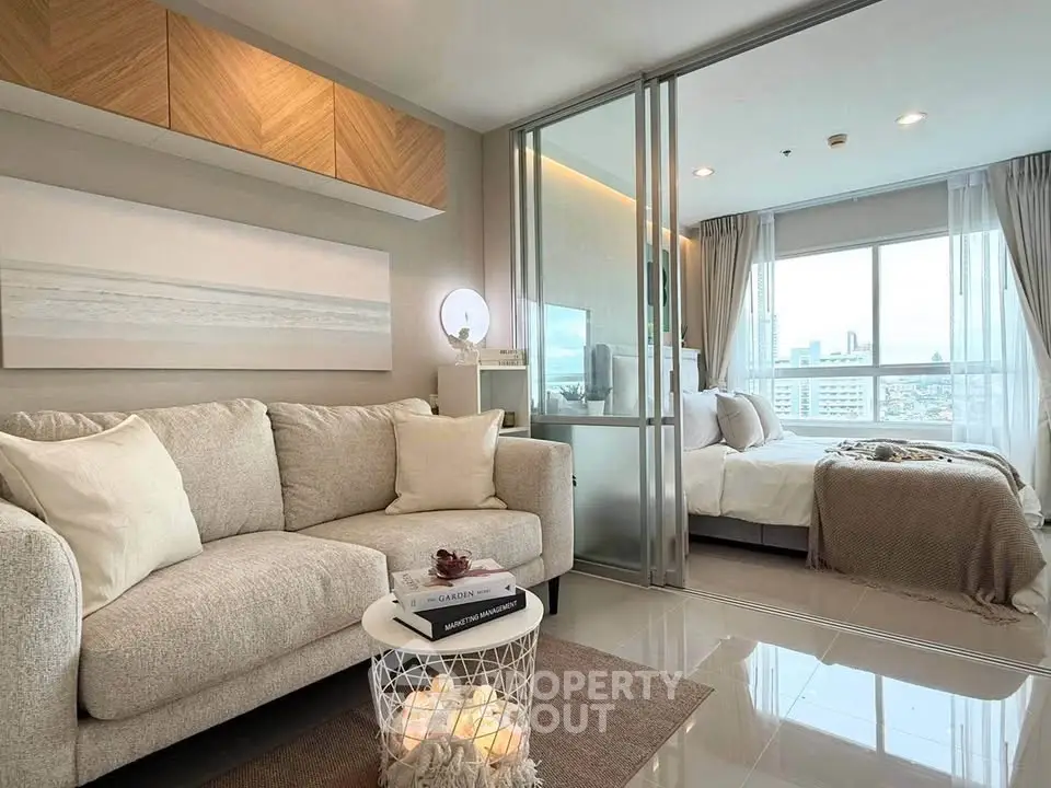 Modern living room with cozy sofa and stylish bedroom view in open-plan apartment.