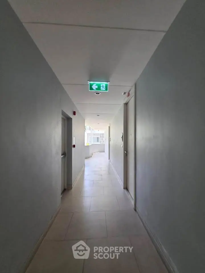 Modern apartment corridor with emergency exit sign and natural light