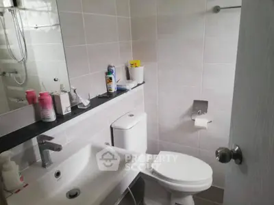 Modern bathroom with sleek fixtures and tiled walls, featuring a compact design.