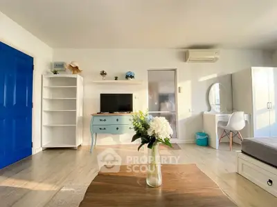 Bright and airy living room with modern decor and blue accents, featuring a TV and stylish furniture.