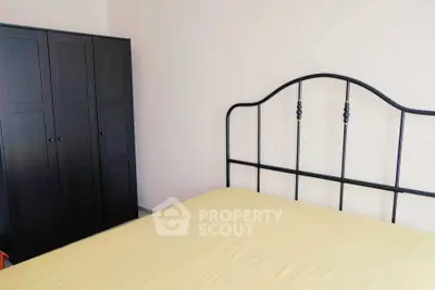 Minimalist bedroom with metal bed frame and dark wardrobe, perfect for modern living.