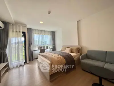 Modern bedroom with cozy bed, stylish sofa, and large window offering scenic views.