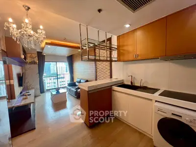 Modern open-layout kitchen and living room with chandelier and city view balcony.