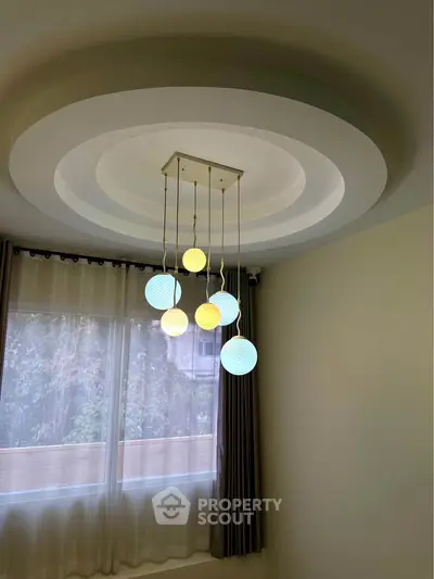 Elegant modern ceiling light fixture in a stylish room with large window and curtains.