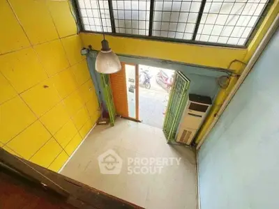 Brightly colored small room with high ceiling and large window, ideal for creative workspace.