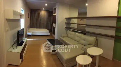 Modern studio apartment with cozy living area and stylish decor, featuring a comfortable sofa and sleek shelving.