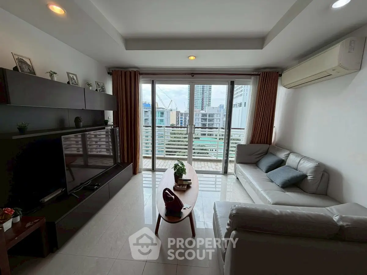 Modern living room with large windows and city view, featuring sleek furniture and stylish decor.