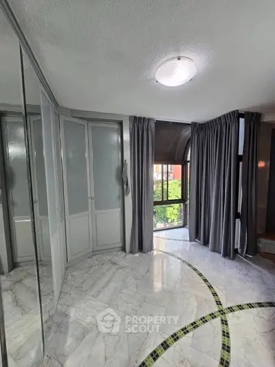 Elegant bedroom with marble flooring and large windows for natural light.