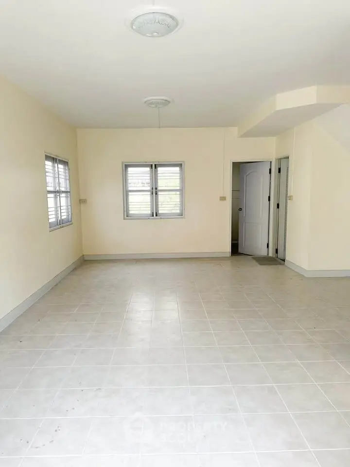 Spacious empty room with tiled flooring and natural light, ideal for customization.