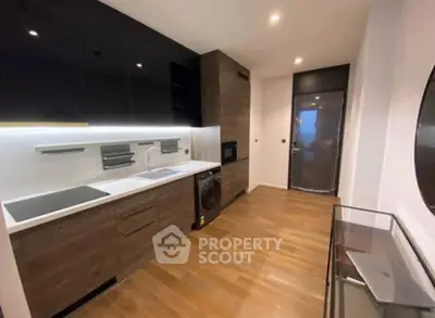 Modern kitchen with sleek cabinetry, built-in appliances, and wooden flooring in a stylish apartment.