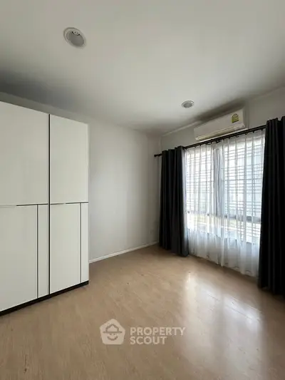 Spacious bedroom with large window and modern wardrobe