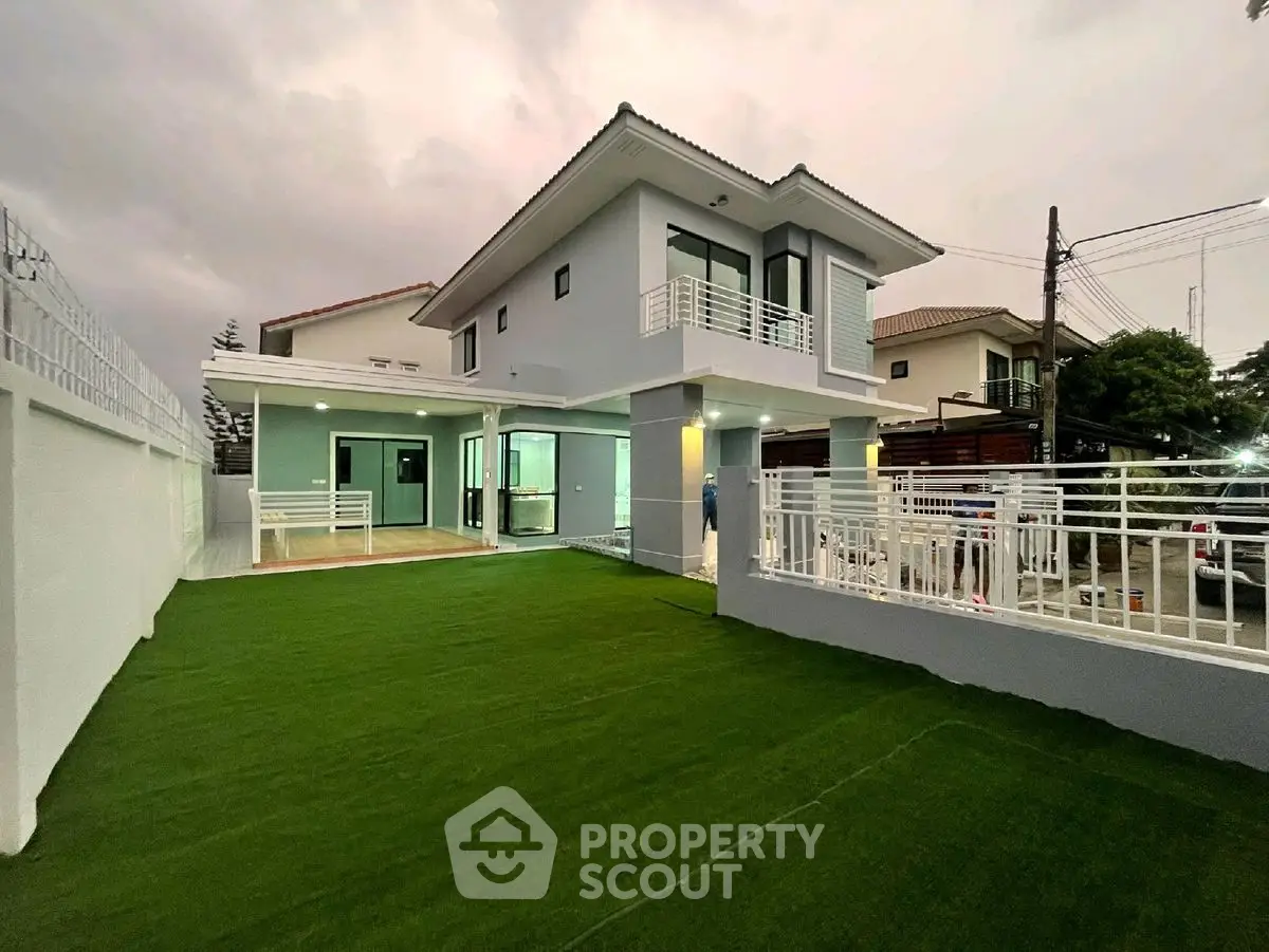 Modern two-story house with spacious lawn and balcony in a serene neighborhood.