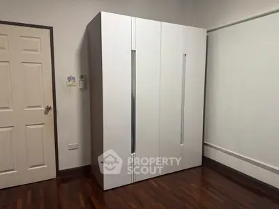 Modern minimalist wardrobe in a sleek bedroom with wooden flooring.