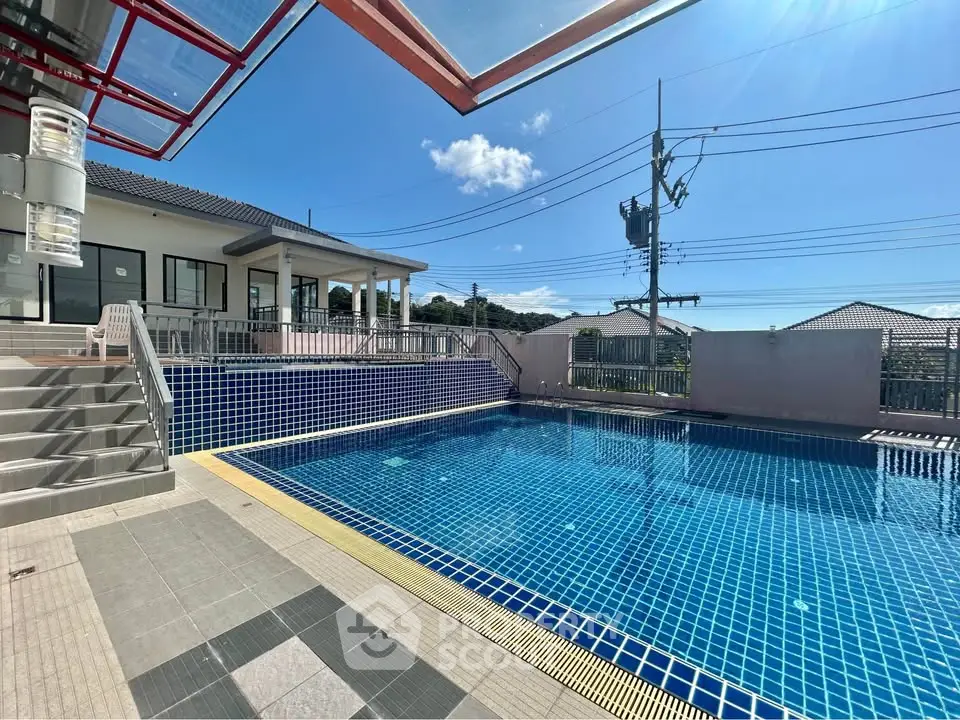 Stunning residential property with a sparkling blue swimming pool and modern architecture under clear skies.