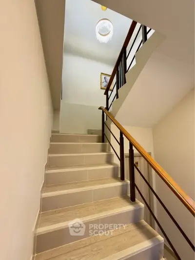 Elegant staircase with modern railing and chandelier in a stylish home interior.