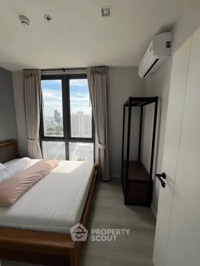 Modern bedroom with large window and city view, featuring minimalist decor and air conditioning.
