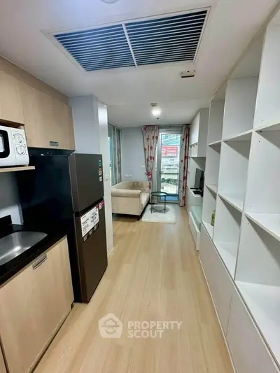 Modern apartment interior with open kitchen and cozy living area, featuring sleek appliances and stylish decor.