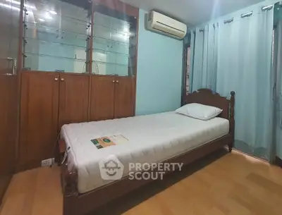 Cozy bedroom with single bed, wooden cabinets, and air conditioning.
