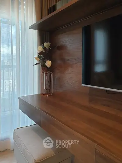 Elegant living room with wooden TV stand and decorative vase near large window with city view.