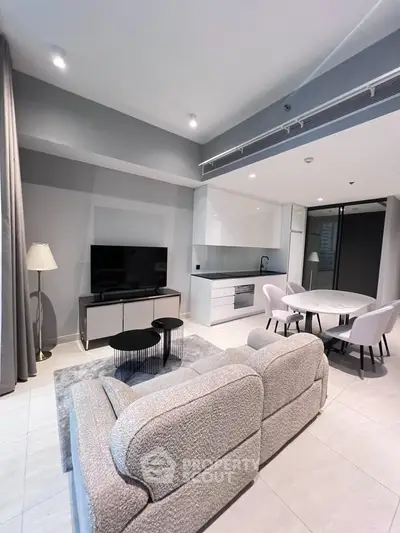 Modern living room with open kitchen, stylish furniture, and sleek design.